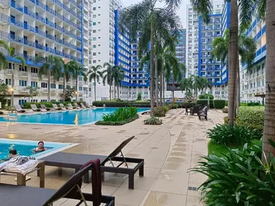a resort pool with palm trees and buildings at SEA RESIDENCES Golden in Manila