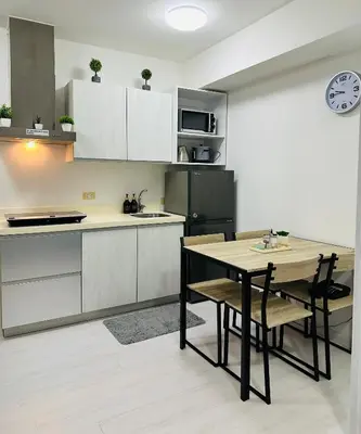 a kitchen with a table and a black refrigerator at Affordable Boracay-like Staycation in Azure South in Manila