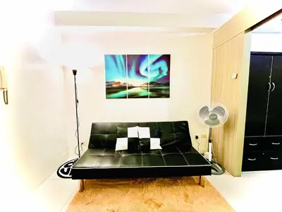 a black leather couch in a room with a painting at Shore Residences in Manila