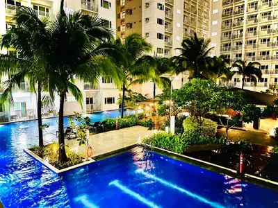 a large swimming pool with palm trees and buildings at Shore Residences in Manila