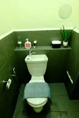 a green bathroom with a toilet with a blue towel at Cecils Cubao Cozy Escape in Manila