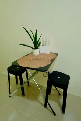 a table with a potted plant and two chairs at Cecils Cubao Cozy Escape in Manila