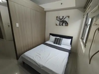 a small bedroom with a bed with white sheets at Shore D 1422 in Manila