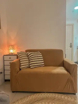 a brown couch in a living room with a lamp at Cozy Condo in Mandaluyong with Balcony, Pool &Netflix in Manila