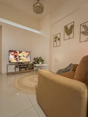 a living room with a couch and a flat screen tv at Cozy Condo in Mandaluyong with Balcony, Pool &Netflix in Manila