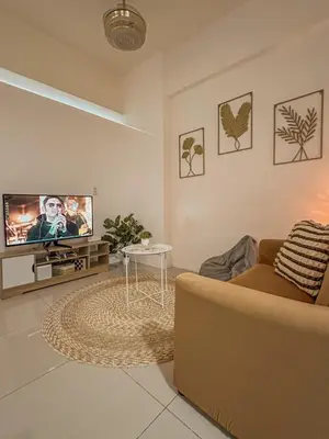 a living room with a couch and a flat screen tv at Cozy Condo in Mandaluyong with Balcony, Pool &Netflix in Manila