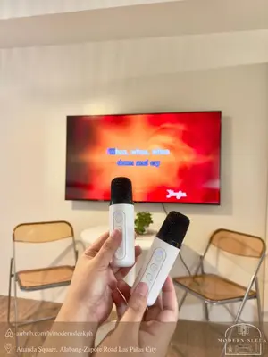 a person holding two wii controllers in front of a tv at Modern Sleek - Staycation in Las Piñas in Manila