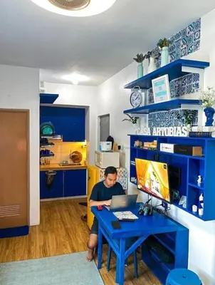 a man sitting at a blue desk with a laptop at Staycation Studio Type in Valley Golf in Cainta