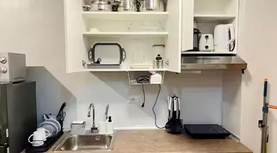 a kitchen with white cabinets and a sink and a counter at Modern Taguig Staycation Near BGC in Manila
