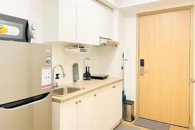 a small kitchen with white cabinets and a sink at Modern Taguig Staycation Near BGC in Manila