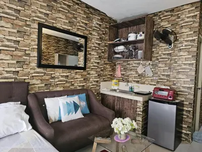 a living room with a couch and a brick wall at Valley Golf Condominium Staycation in Cainta