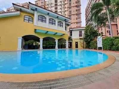 a large swimming pool in front of a building at Modern Studio Condominium 1 in Manila