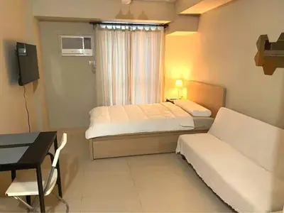 a hotel room with a bed and a desk and a bedroom at Modern Studio Condominium 1 in Manila