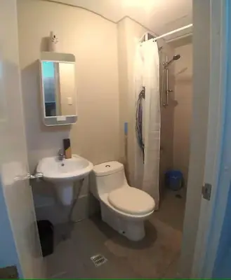 a white bathroom with a toilet and a sink at Modern Studio Condominium 1 in Manila