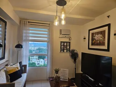 a living room with a television and a window at Cozy 3-Bedroom Family Condo in Manila