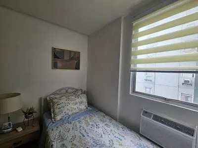 a small bedroom with a bed and a window at Cozy 3-Bedroom Family Condo in Manila