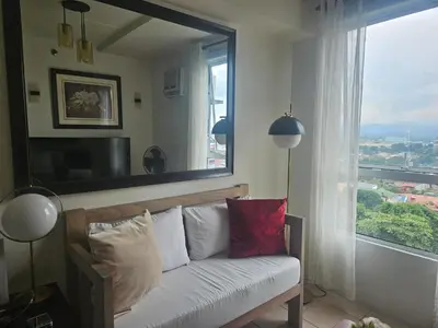 a living room with a couch and a large window at Cozy 3-Bedroom Family Condo in Manila
