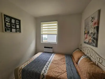 a bedroom with a bed and a window at Cozy 3-Bedroom Family Condo in Manila
