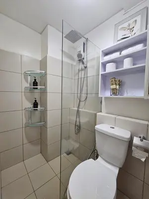 a bathroom with a toilet and a glass shower at Cozy 3-Bedroom Family Condo in Manila