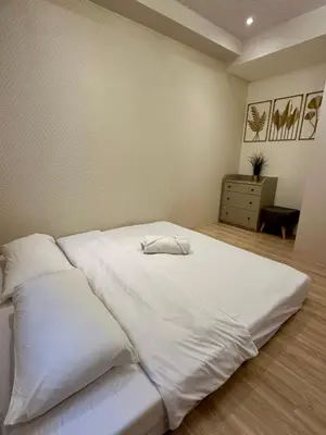 a white bed with two pillows in a bedroom at Amazing Sunrise View 2 Bed Room, QLED 65-Inch Samsung TV, Disney & Max, Max 5 Adult and 2 kids in Manila