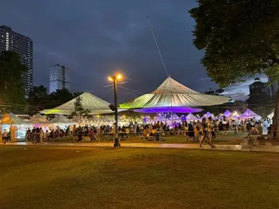 a group of people walking under tents in a park at night at Amazing Sunrise View 2 Bed Room, QLED 65-Inch Samsung TV, Disney & Max, Max 5 Adult and 2 kids in Manila
