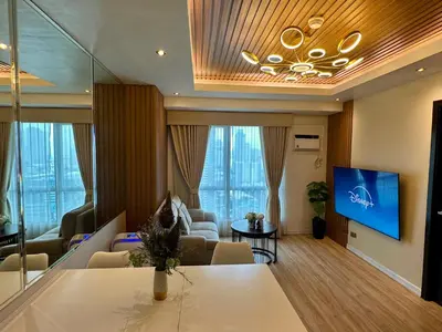 a living room with a couch and a tv on a wall at Amazing Sunrise View 2 Bed Room, QLED 65-Inch Samsung TV, Disney & Max, Max 5 Adult and 2 kids in Manila