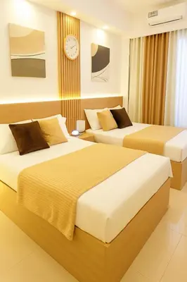 two beds in a hotel room with a clock on the wall at Shore 2 Residences in Manila