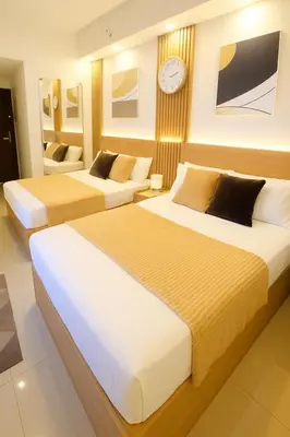 two beds in a hotel room with a clock on the wall at Shore 2 Residences in Manila