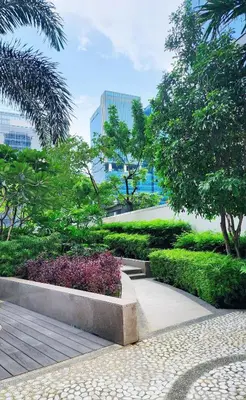 a park with trees and bushes and a sidewalk at Andi and Frances Place at BGC in Manila