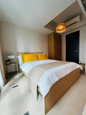 a bedroom with a large bed with yellow pillows at Andi and Frances Place at BGC in Manila