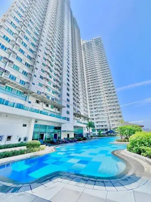 a large building with a large blue pool in front of it at The Beacon Makati Condo-Hotel in Manila