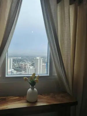 a vase with flowers sitting on a table in front of a window at The Beacon Makati Condo-Hotel in Manila