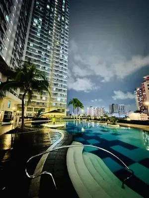 a large swimming pool in a city with a tall building at The Beacon Makati Condo-Hotel in Manila