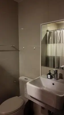 a white bathroom with a toilet and a sink at Cozy place in Uptown BGC near Malls and clubs in Manila