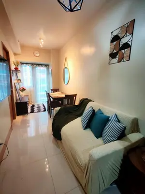 a living room with a bed and a dining room at CabinandCo in Manila
