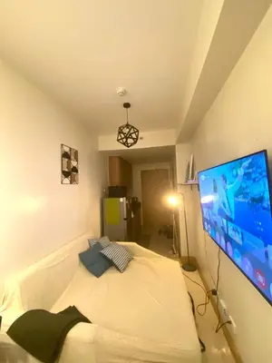 a bedroom with a bed with a large tv on the wall at CabinandCo in Manila