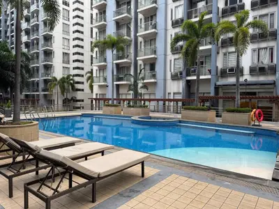 a swimming pool with two chaise lounges next to a building at Newport Stay Walk to NAIA T3 in Manila