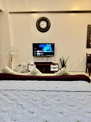 a bedroom with a bed and a tv and a clock at Newport Stay Walk to NAIA T3 in Manila