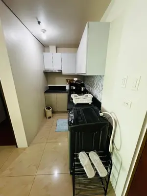 a small kitchen with white cabinets and a dishwasher at Amorsolo Tower Makati in Manila