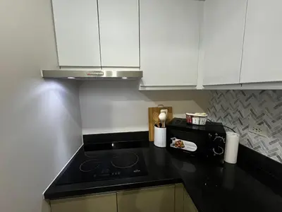 a kitchen with white cabinets and a black counter top at Amorsolo Tower Makati in Manila