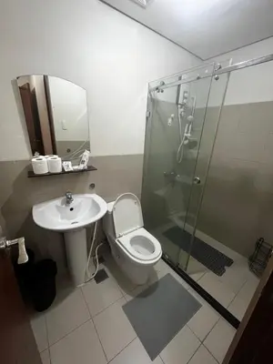 a bathroom with a shower and a toilet and a sink at Amorsolo Tower Makati in Manila