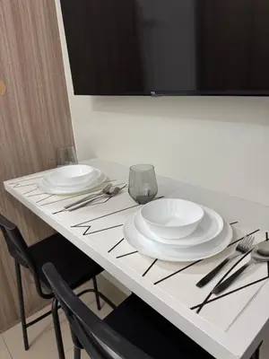 a table with two white plates and silverware on it at Metro Prime Staycations at Shore 2 Residences T1 in Manila
