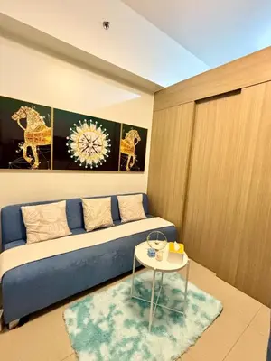 a bedroom with a blue couch and a table at Poolside Bliss at Shore 2 in Manila