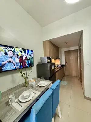 a dining room table with blue chairs and a tv at Poolside Bliss at Shore 2 in Manila