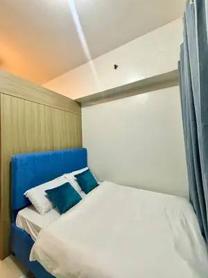 a bed with a blue headboard in a room at Poolside Bliss at Shore 2 in Manila