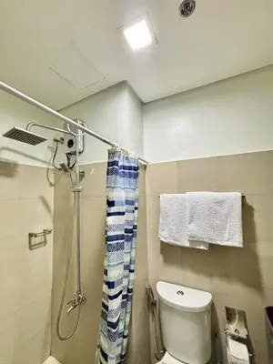 a bathroom with a shower and a toilet and towels at Poolside Bliss at Shore 2 in Manila