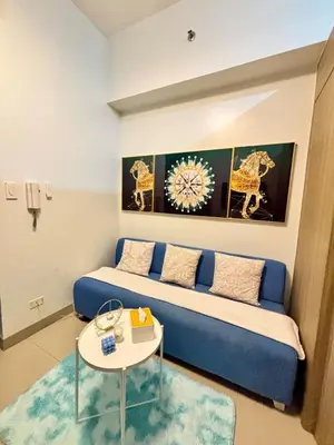 a living room with a blue couch and a table at Poolside Bliss at Shore 2 in Manila