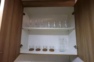 a row of glasses sitting on shelves in a cabinet at Modern Living 6 - MOA Pasay with Wifi and Netflix in Manila