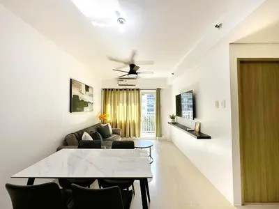 a dining room and living room with a table and chairs at Spacious 2BR Living Rm Shore Res near NAIA MOA in Manila