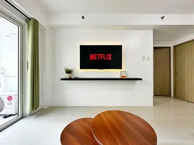 a living room with a table and a netflix sign on the wall at Spacious 2BR Living Rm Shore Res near NAIA MOA in Manila